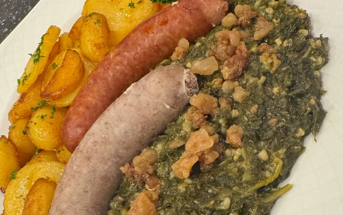 Teller mit Grünkohl, Pinkelwurst, Mettwurst, Grieben und Bratkartoffeln